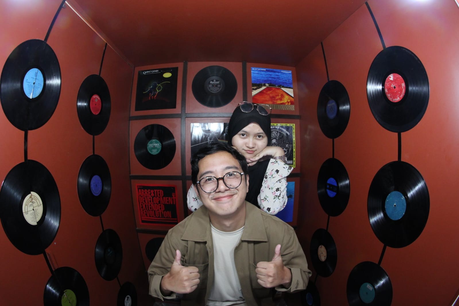 Foto first date Reno dan Ridaaa di photobooth berlatar kaset dan piringan hitam